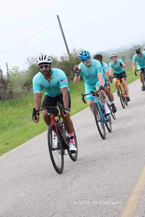 Bright Bluebonnet Express cycling team riding on scenic rural road for outdoor bike race.