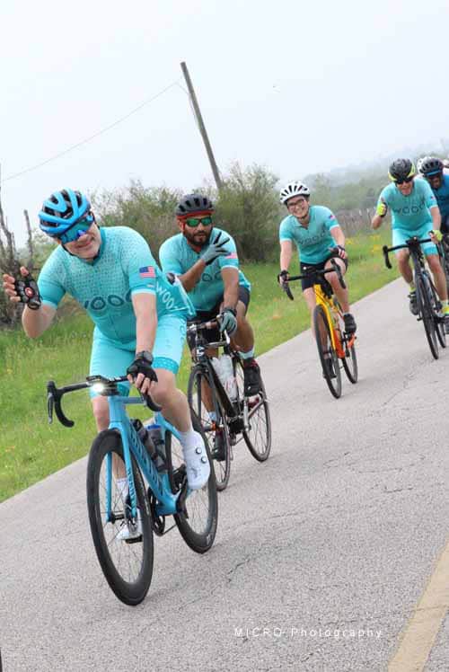 Bright blue cycling team riding on scenic country road during Bluebonnet Express event.
