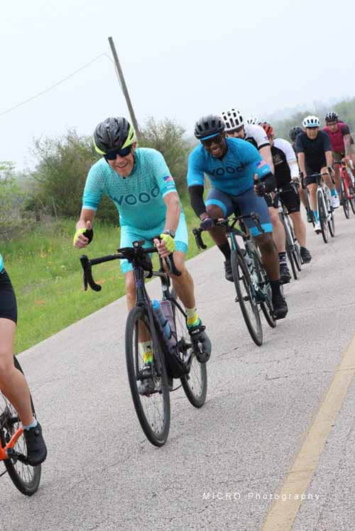 Brightly dressed cyclists riding together on a rural road during Bluebonnet Express.