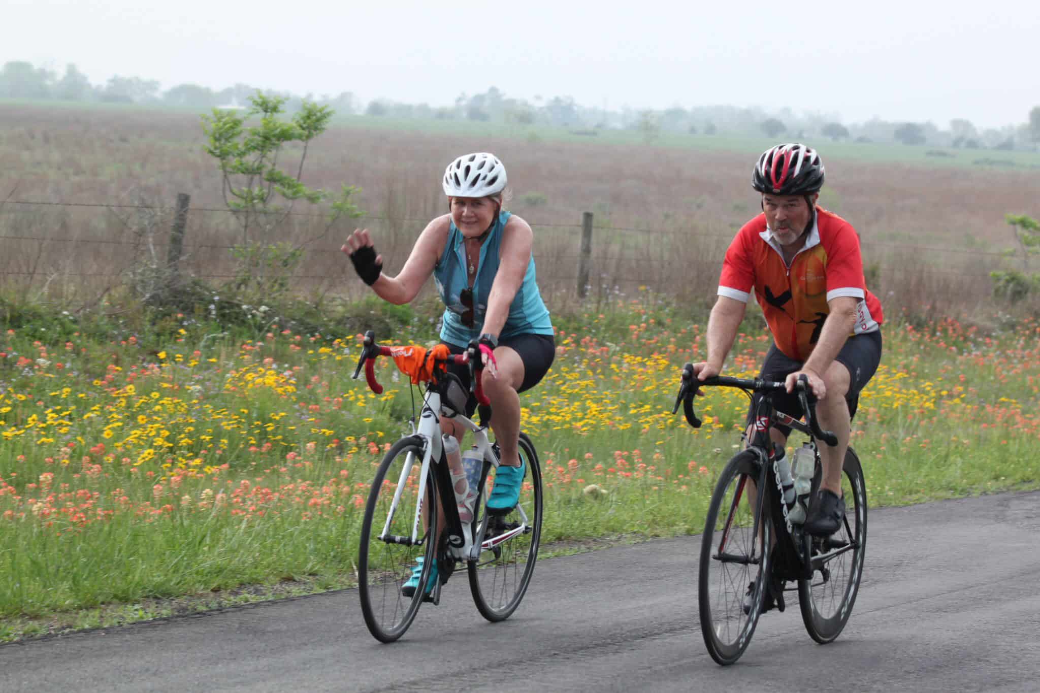 Vibrant outdoor cycling shot of seniors riding bikes along a scenic road with colorful wildflowers.