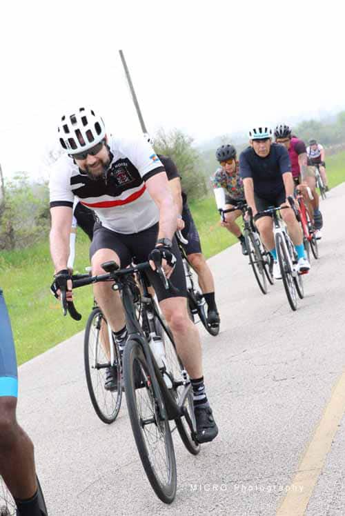 Brightly dressed cyclists riding together on a scenic outdoor path during Bluebonnet Express event.