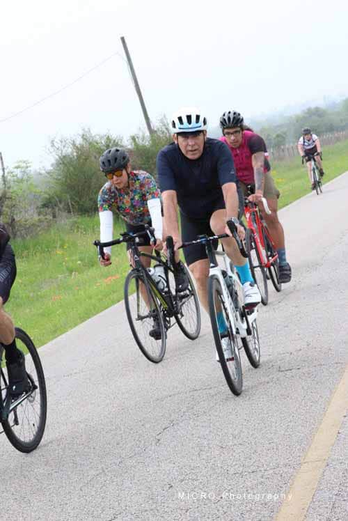 Brightly dressed cyclists riding on scenic Bluebonnet Express trail in Texas countryside.