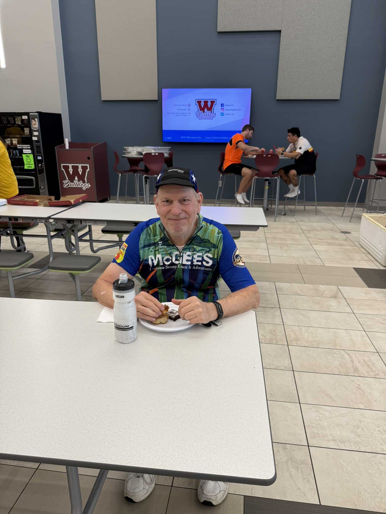 Bright man in cycling jersey enjoying meal at Bluebonnet Express, Texas cycling stop.