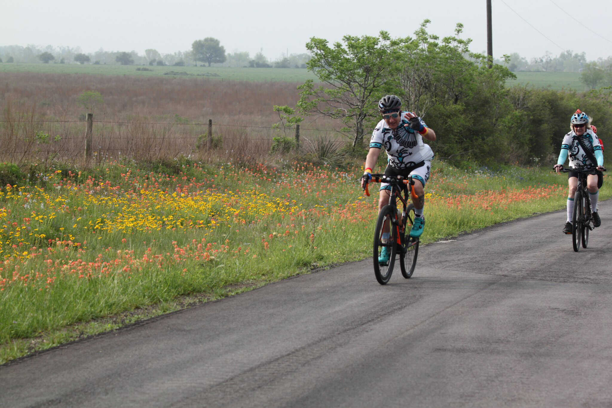 Vibrant cyclists riding through scenic wildflower fields on the Bluebonnet Express route.