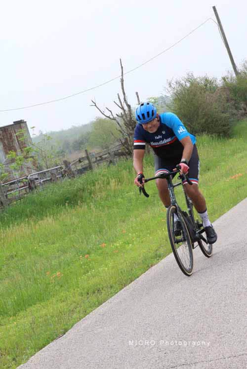 Dynamic cyclist riding on scenic rural road during daytime.