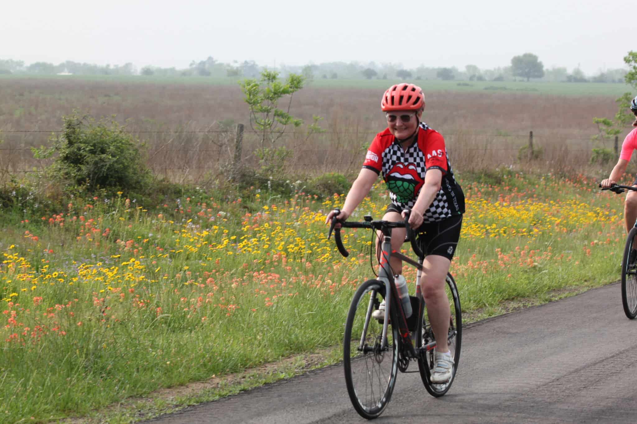 Bright young woman cycling on scenic rural road during outdoor Orange Blossom Festival, cheerful and eco-friendly transportation.