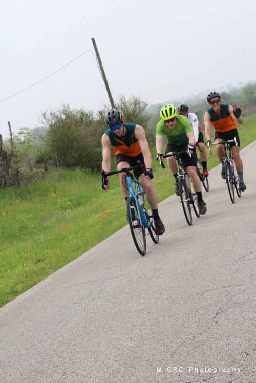 Brightly dressed cyclists riding on a rural trail during daytime, enjoying outdoor biking adventure.