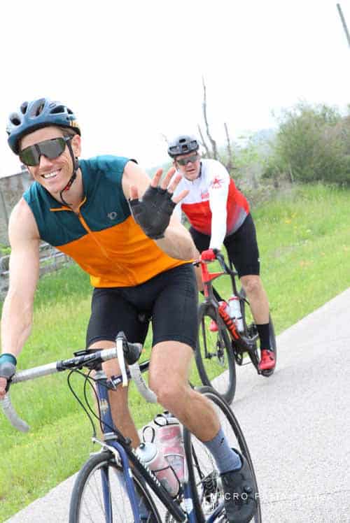 Bright smiling cyclist waving on scenic outdoor trail during Bluebonnet Express bike event.