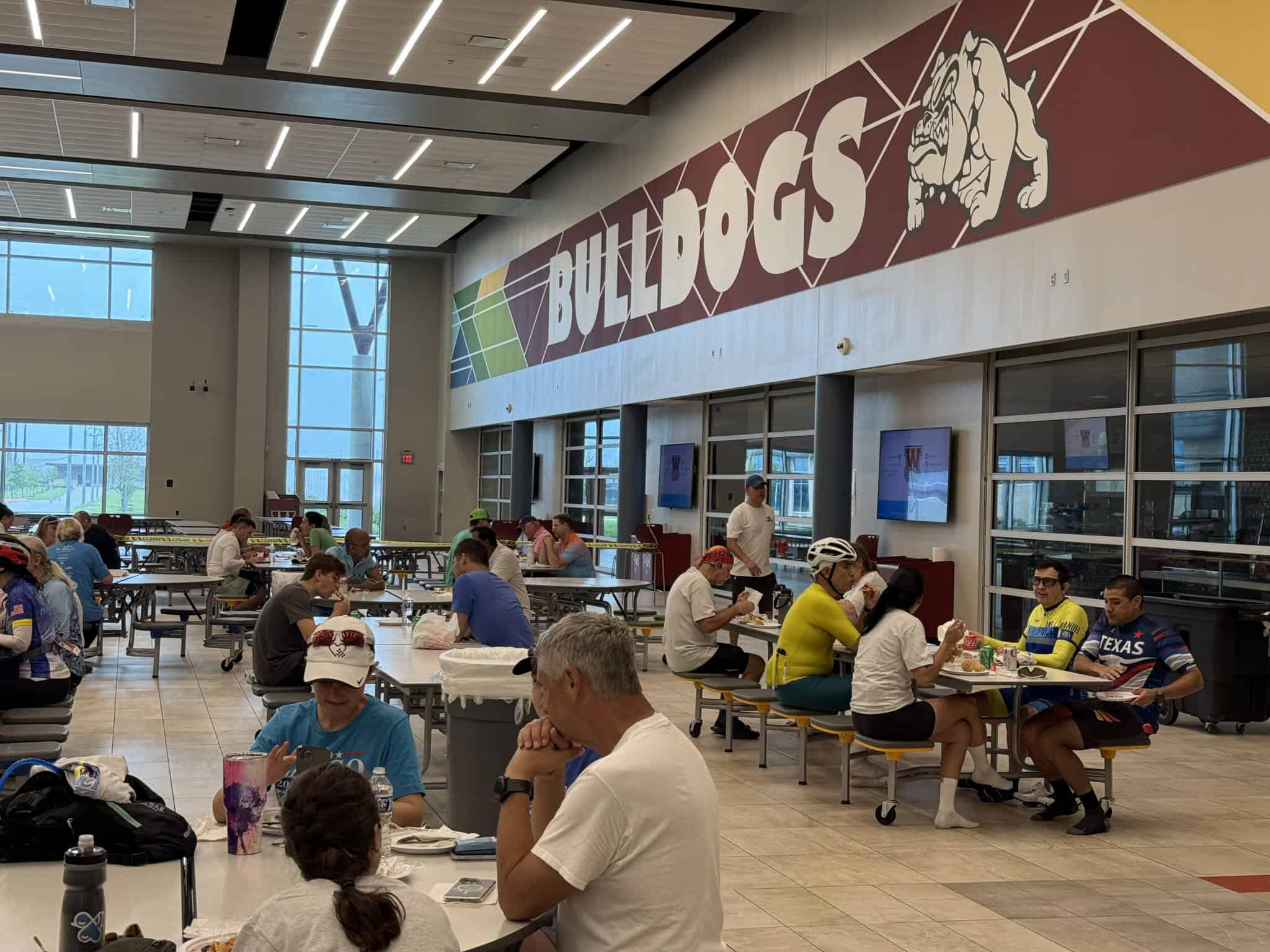 Bright indoor dining area at Bulldog athletic facility, bustling with diverse people enjoying meals.
