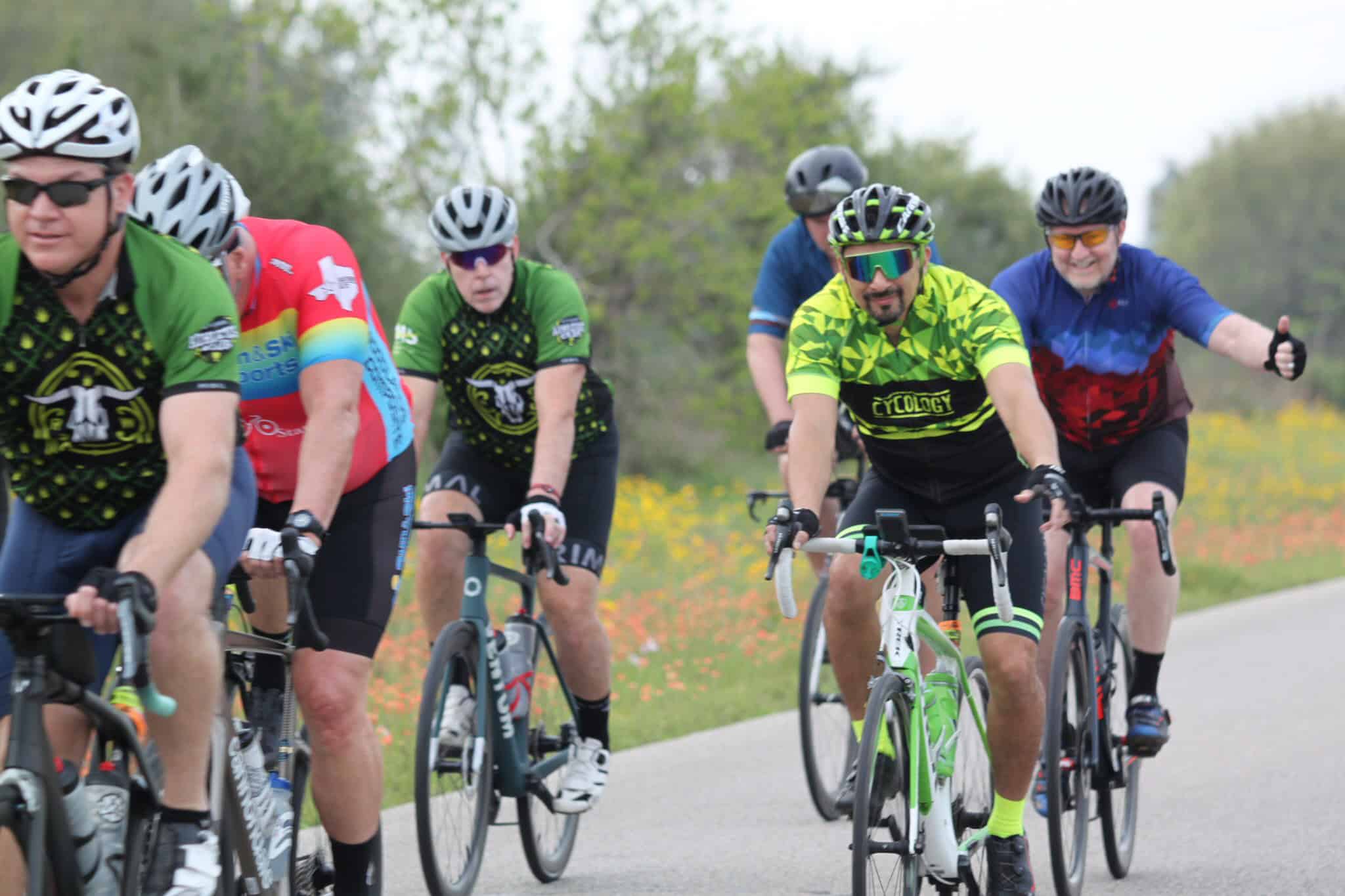 Vibrant cyclists riding together on scenic park trail, promoting Bluebonnet Express cycling event.
