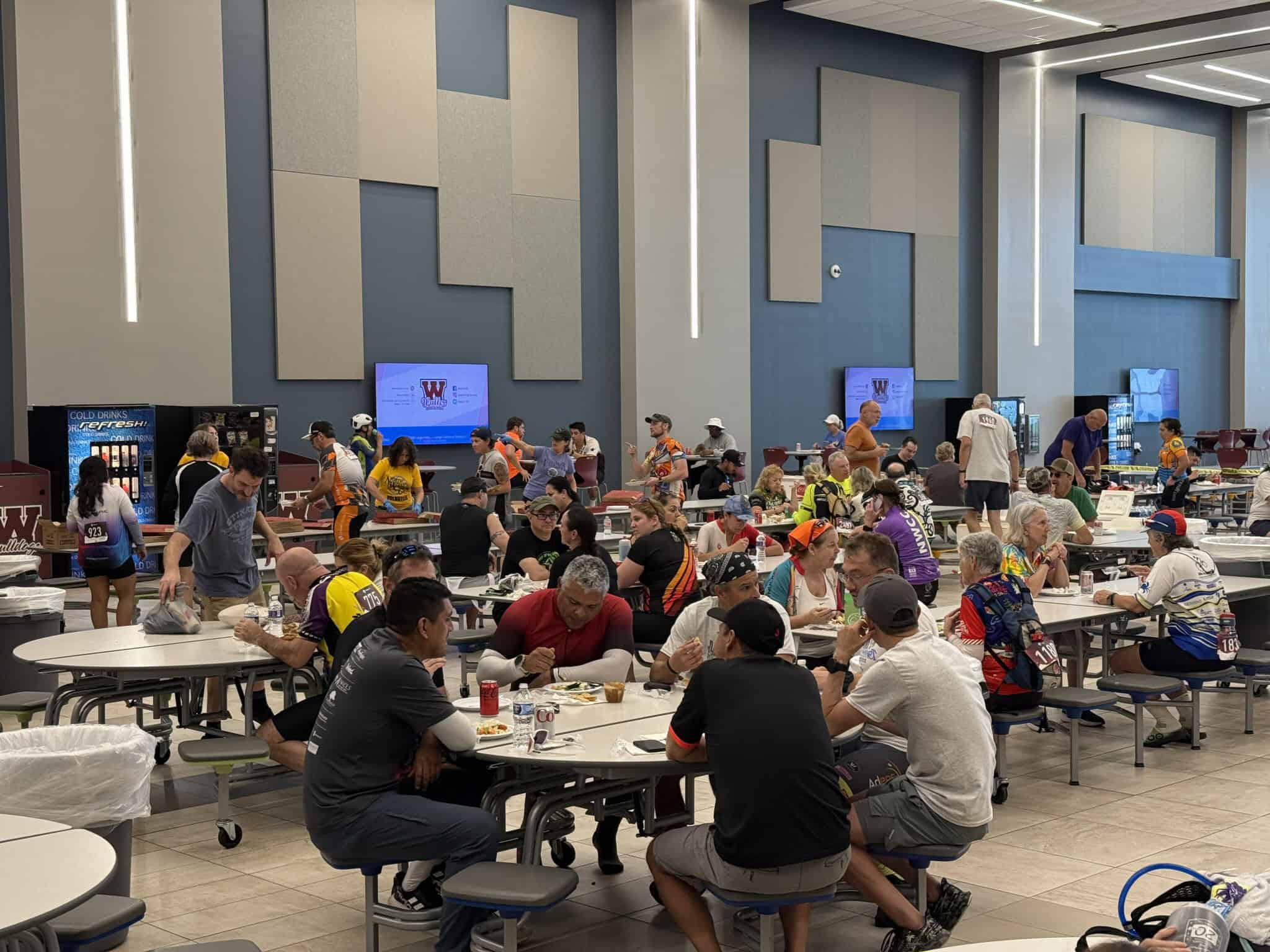 Brightly lit indoor dining area at Bluebonnet Express event, filled with cyclists and spectators enjoying meals.