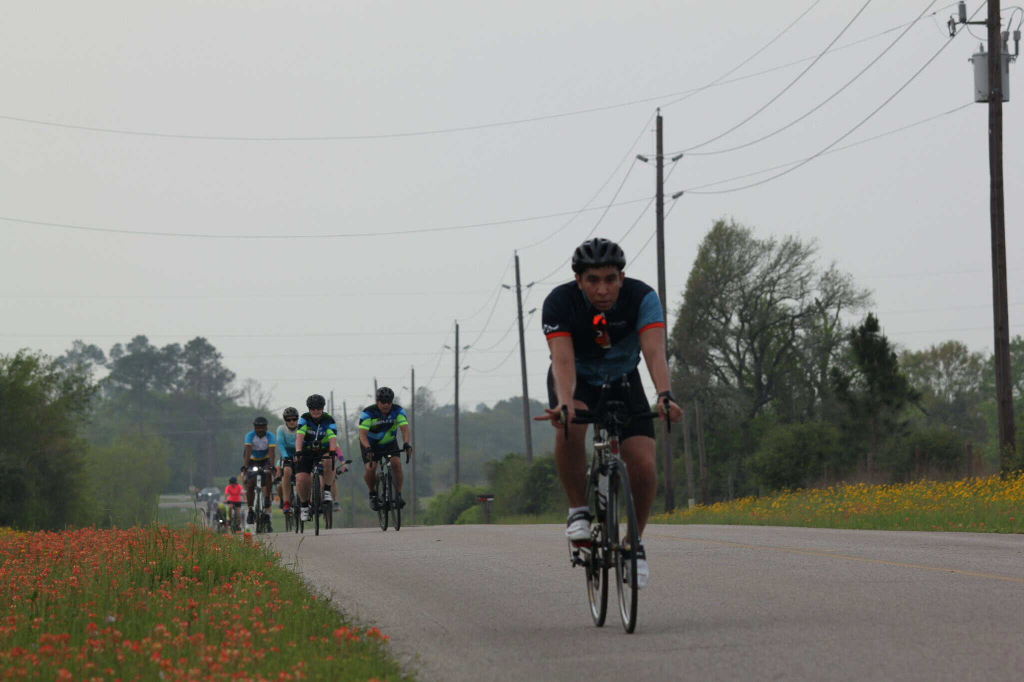 Cyclists riding on rural road during Bluebonnet Express bike race in Texas.