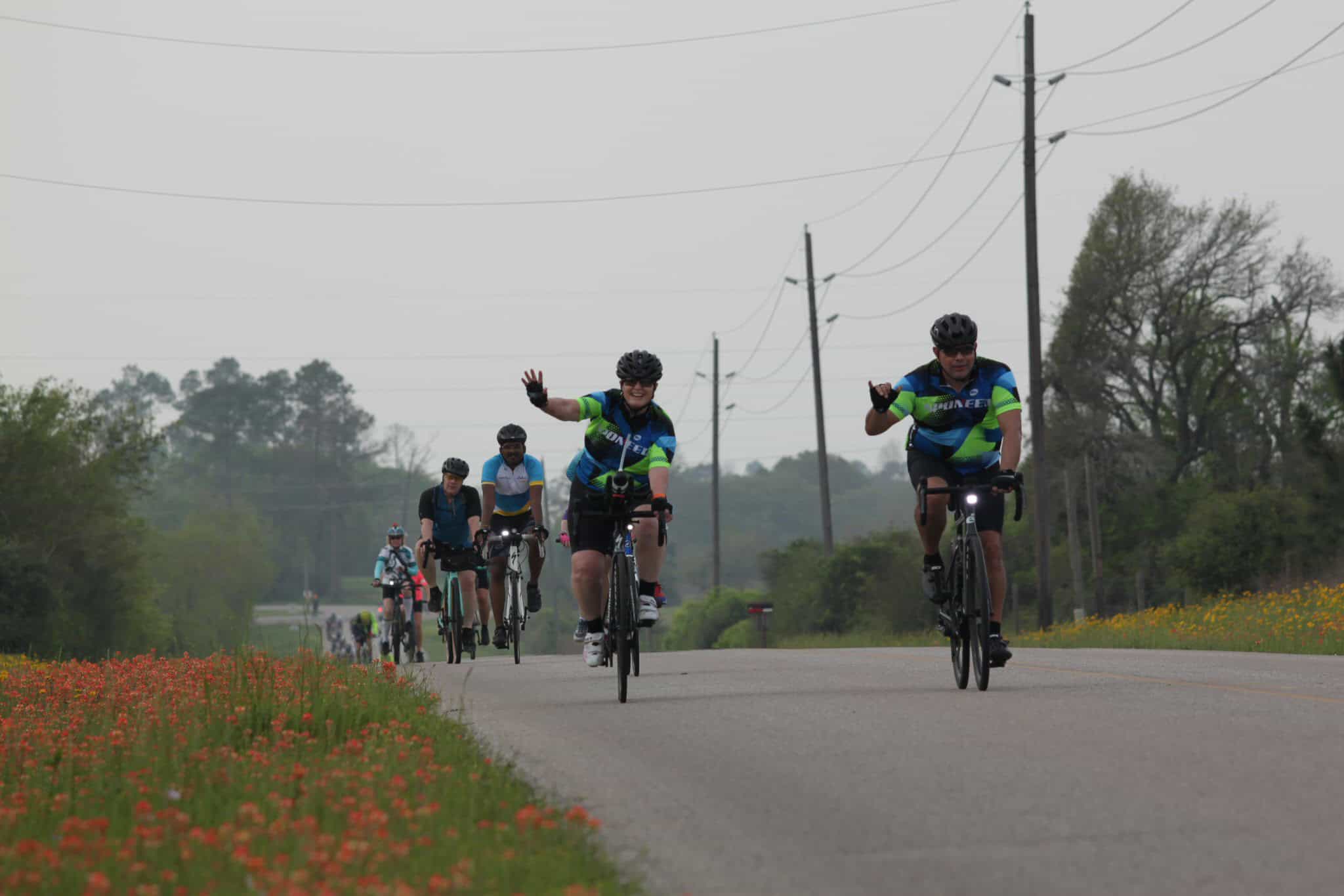 Active cyclists riding on a rural road, promoting Bluebonnet Express bike tours and outdoor adventure.