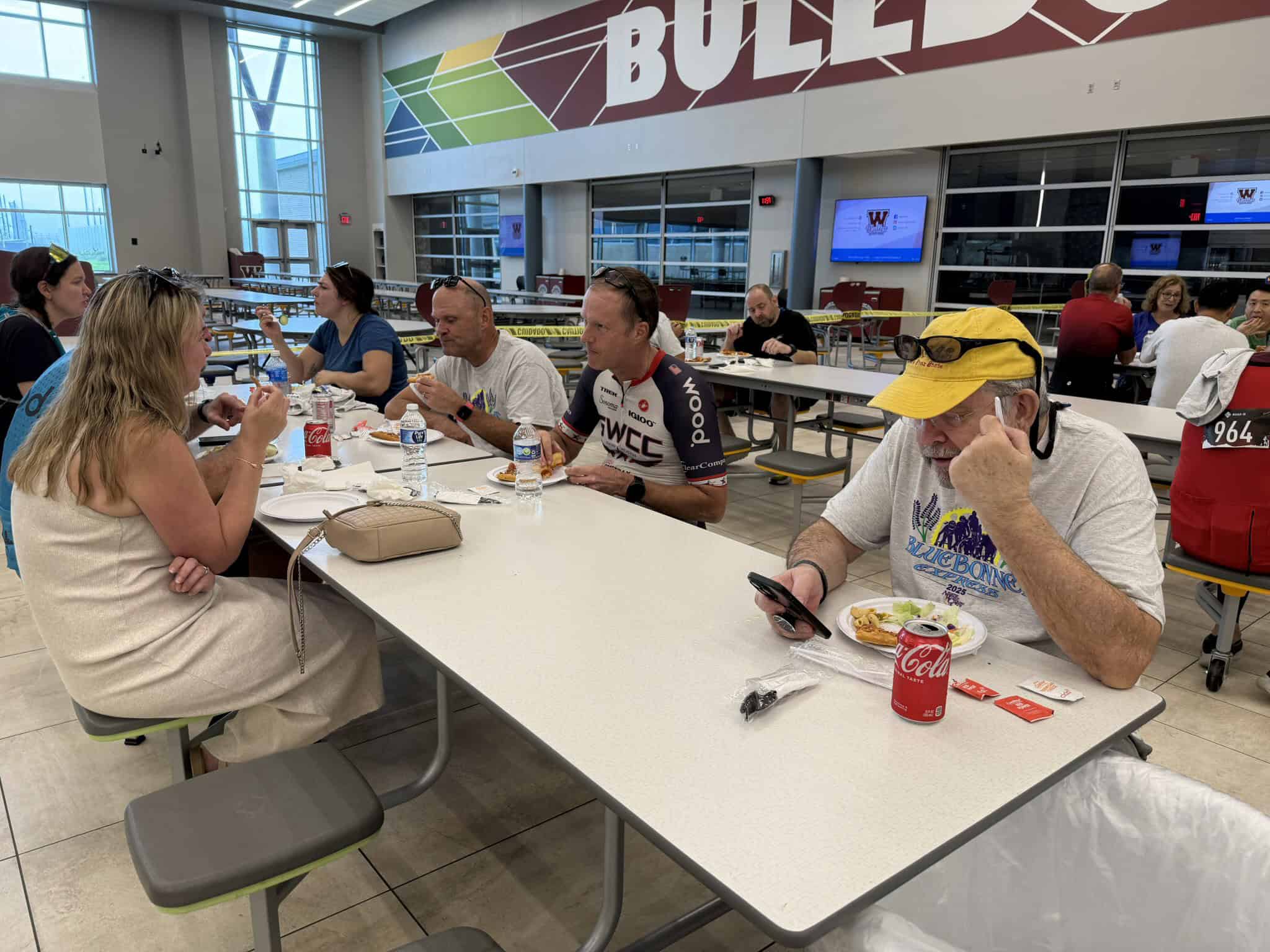 Bright indoor dining area featuring Bluebonnet Express event participants enjoying a meal at a long table, showcasing a lively, community-oriented atmosphere.