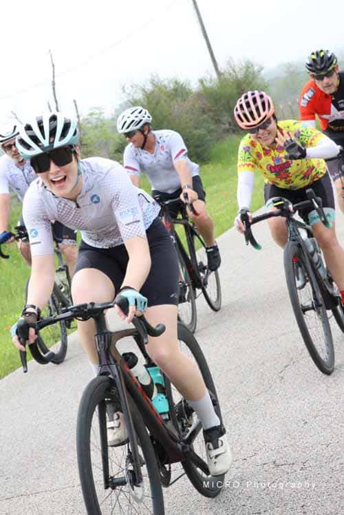 Velo cyclists riding on scenic outdoor trail with lush greenery for Bluebonnet Express event.