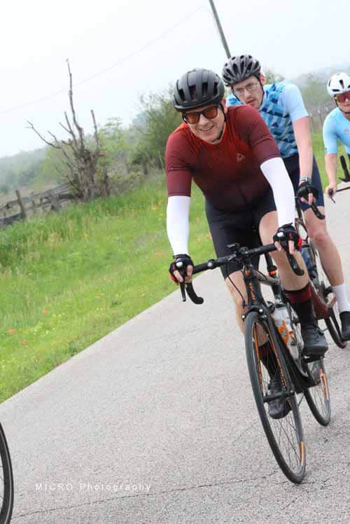 Cyclists riding in scenic countryside with Bluebonnet Express logo, promoting cycling events and outdoor adventures.