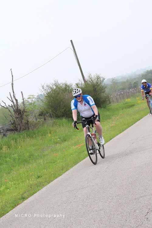 Cyclist riding along a scenic rural road during the Bluebonnet Express event.