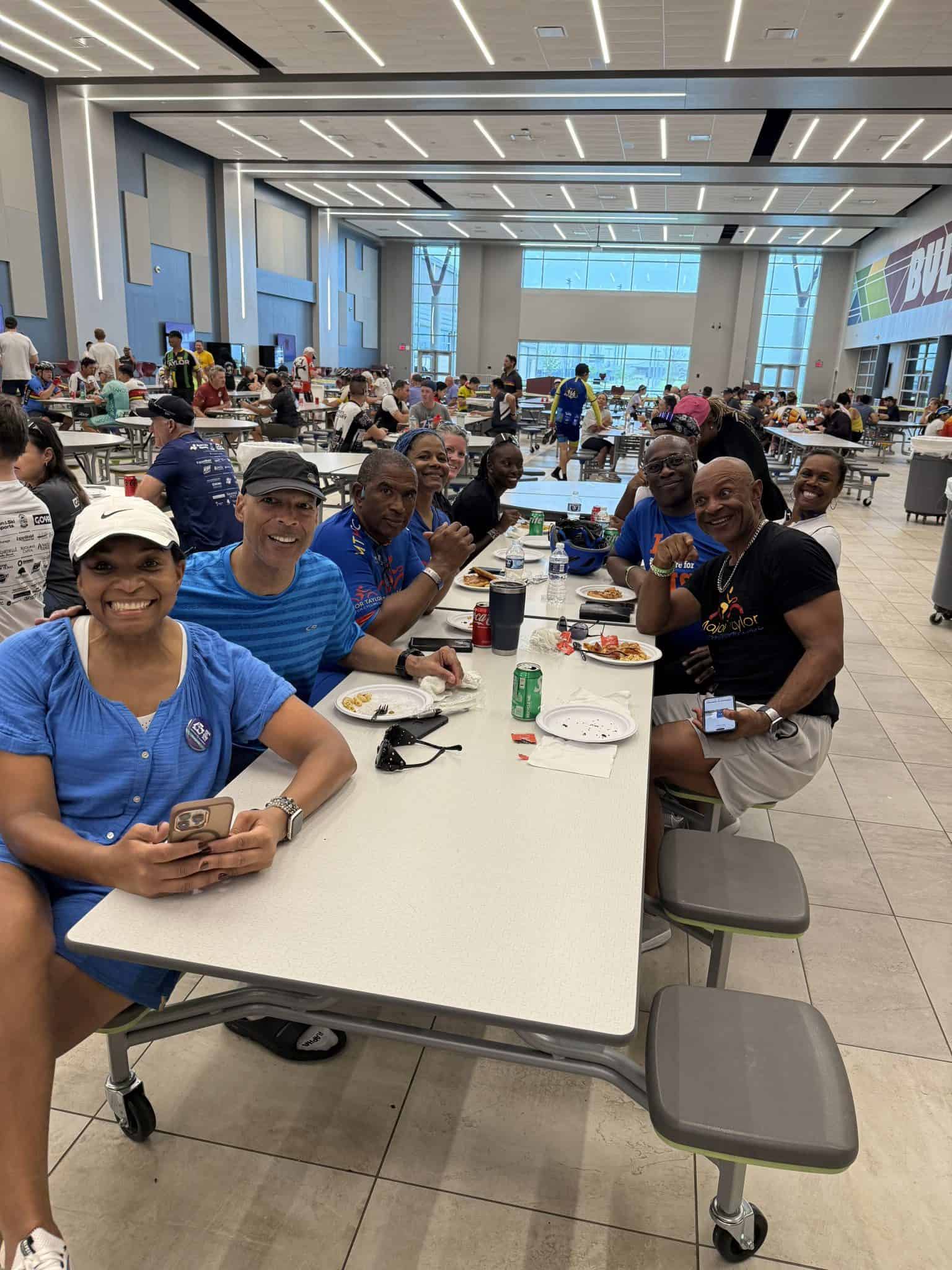 Lively group enjoying meals at Bluebonnet Express dining hall during cycling event.