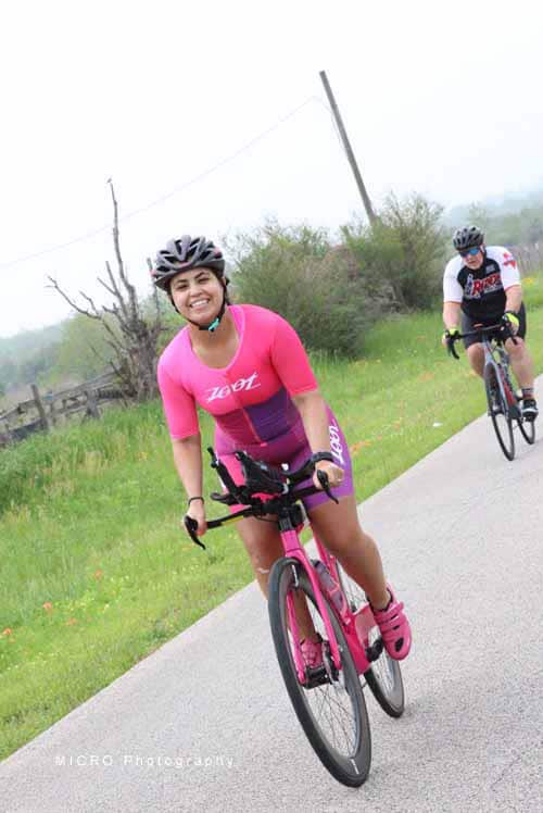 Bright woman riding pink bicycle on scenic outdoor trail, enjoying cycling adventure with friends.
