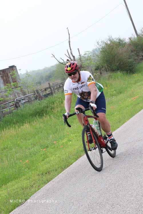 Vibrant cyclist on a scenic bike ride along a countryside road with lush greenery.