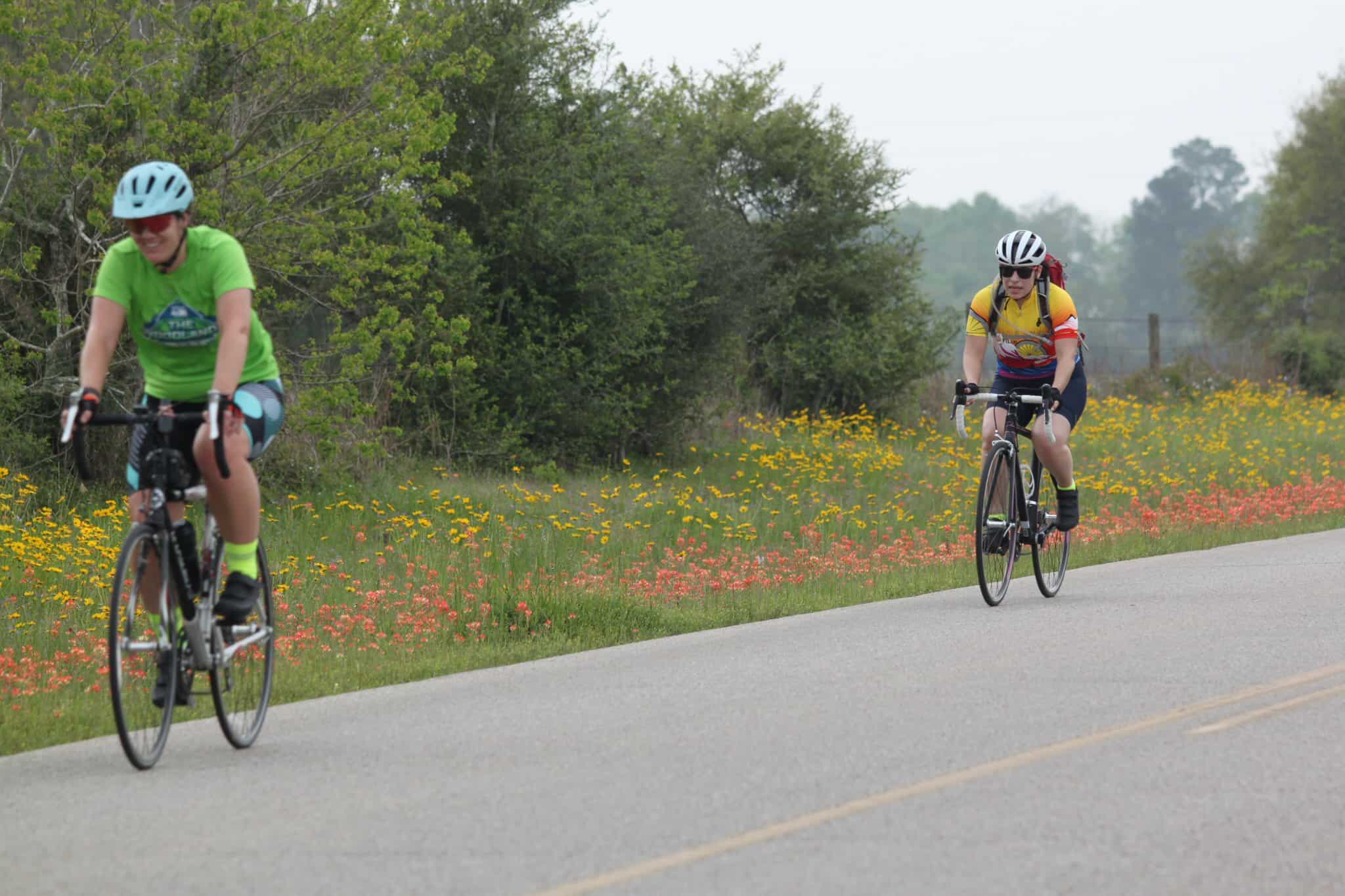 Vibrant cyclists riding along blooming roadside during Bluebonnet Express event in Texas.