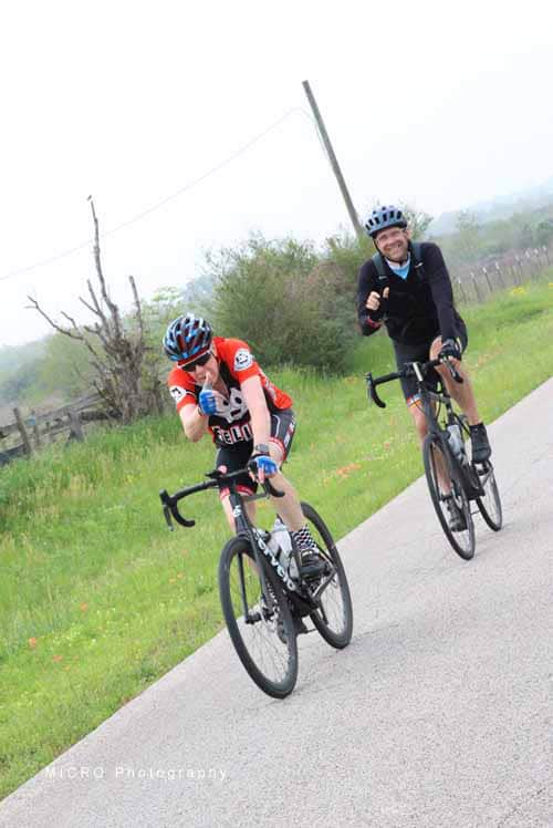 Brightly dressed cyclists riding on a scenic rural trail during daytime, promoting Bluebonnet Express bike tours.