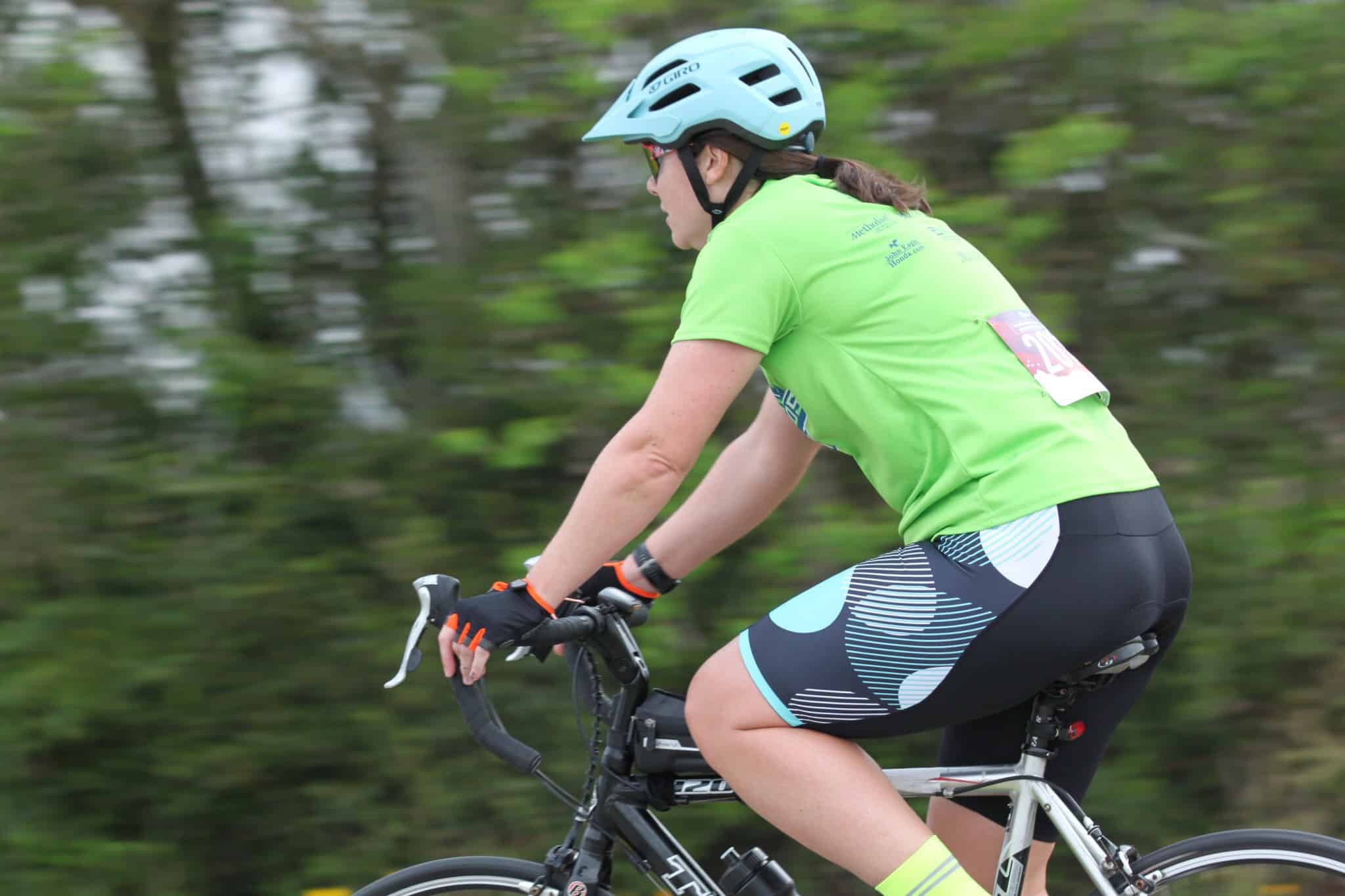 High-energy cyclist riding mountain bike on trail with green foliage.