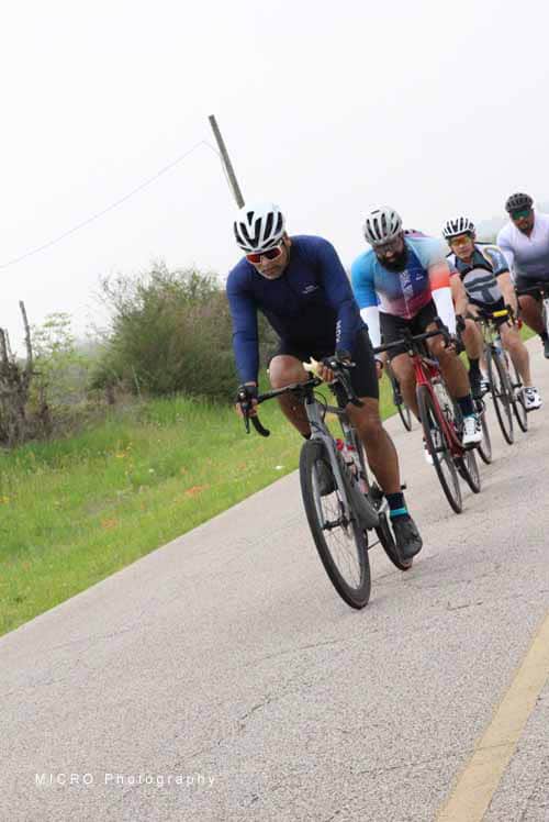 High-performance cyclists riding on scenic rural road, promoting Bluebonnet Express bike event.