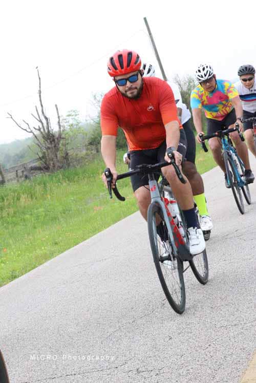 Vibrant group cycling on scenic countryside road during Bluebonnet Express event.