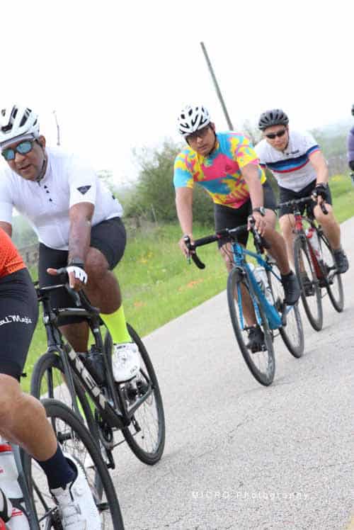 Vibrant group of cyclists on a scenic outdoor ride featuring Bluebonnet Express jerseys and bikes.