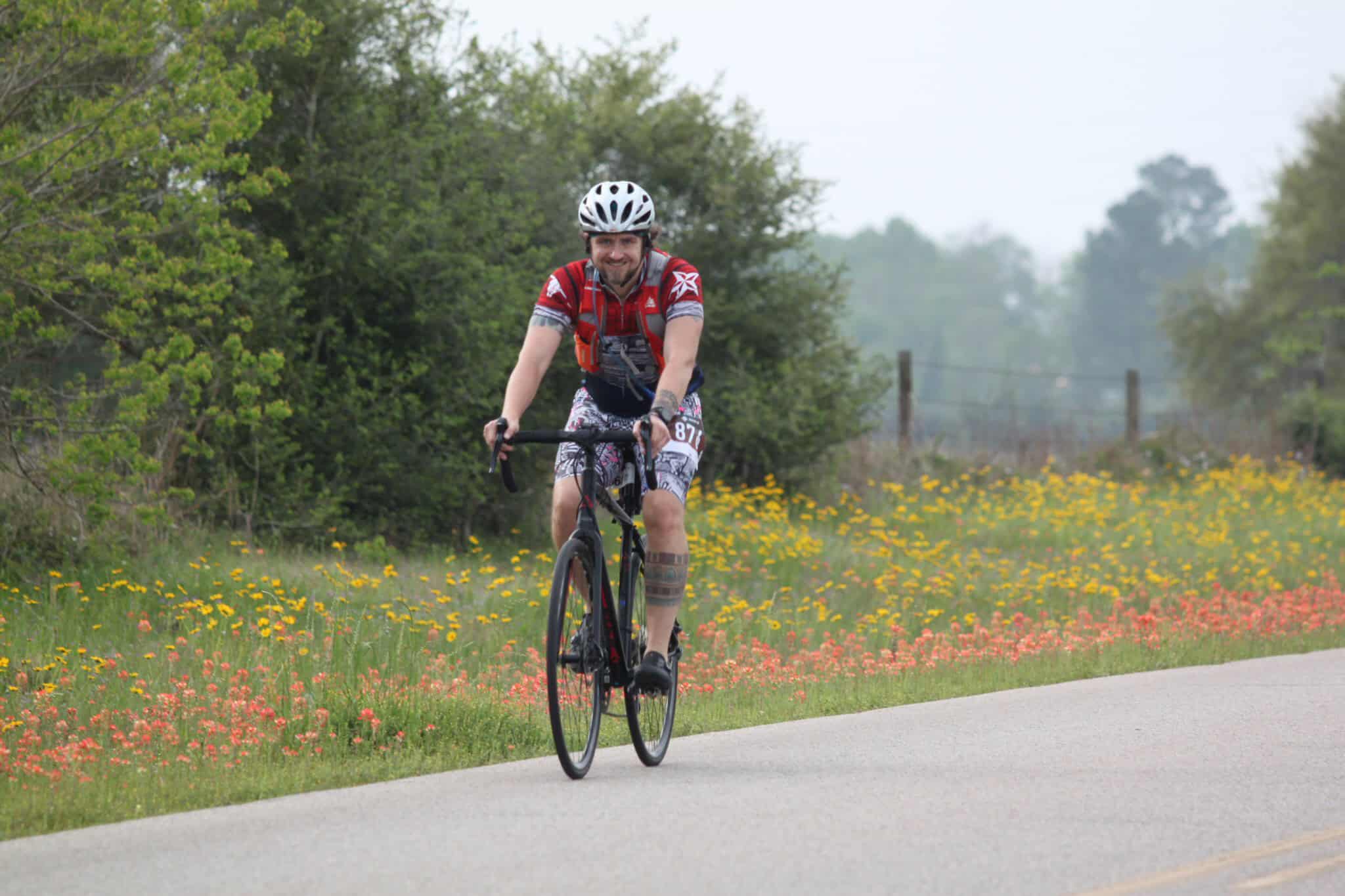 Bright male cyclist riding on scenic countryside road in Bluebonnet Express event, enjoying outdoor biking adventure.