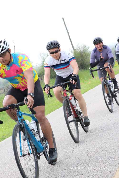 Vibrant cyclists riding on scenic road during Bluebonnet Express event.