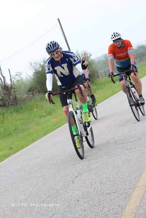 Vuelta Cycling Team riding bikes on scenic rural road during daytime.