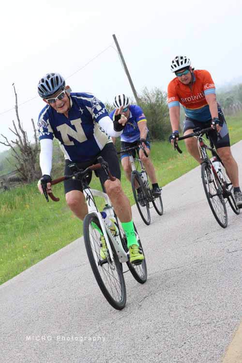 1. Group cycling on a scenic rural road with Bluebonnet Express event banners.
