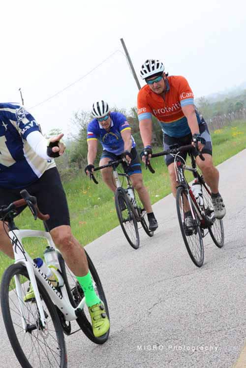 1. Group of cyclists riding on scenic road during daytime, mountain biking event.