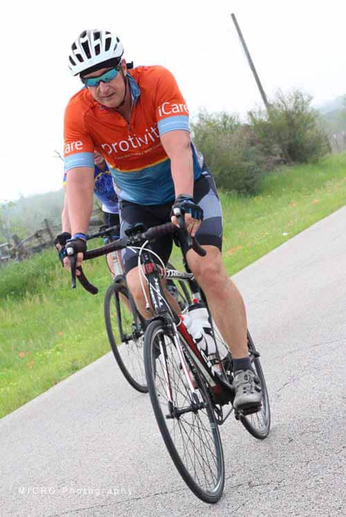 Active cyclist riding a bike on a scenic outdoor trail, promoting Bluebonnet Express cycling event organizer.