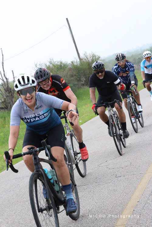 Active cyclists riding on scenic rural road during Bluebonnet Express event, promoting fitness and outdoor recreation.