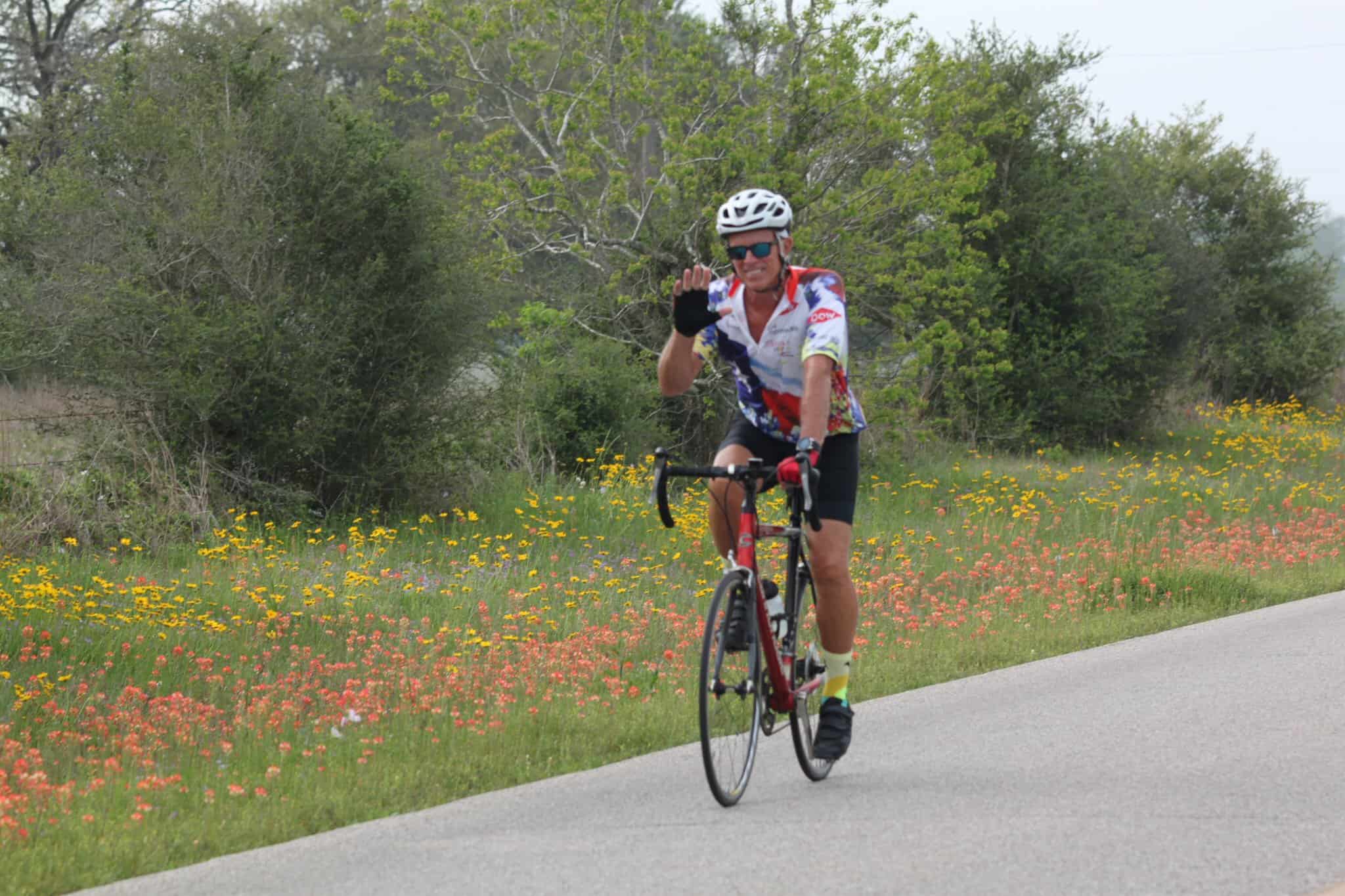 Bright cyclist enjoying scenic ride on Bluebonnet Express bike trail with colorful wildflowers.