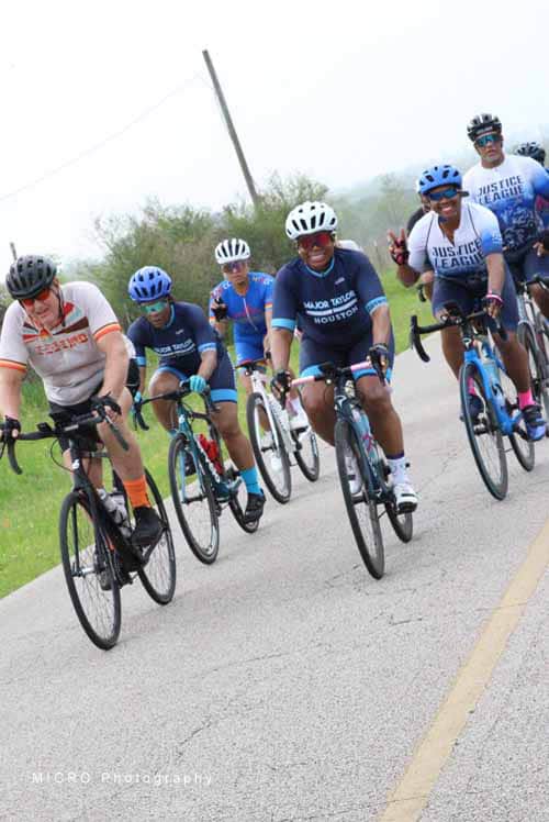 Brightly colored cyclists participating in Bluebonnet Express charity bike ride on a rural road.