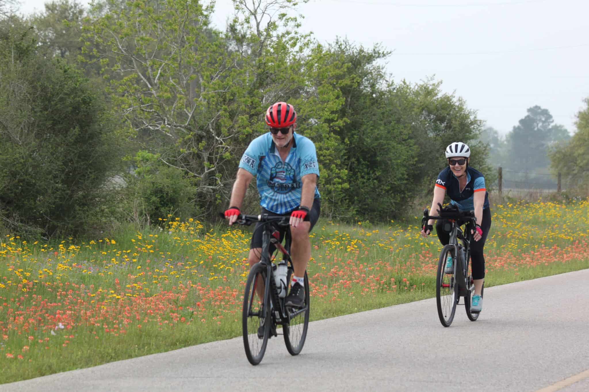 Vibrant cyclists riding on scenic trail among wildflowers and greenery, promoting Bluebonnet Express cycling events.