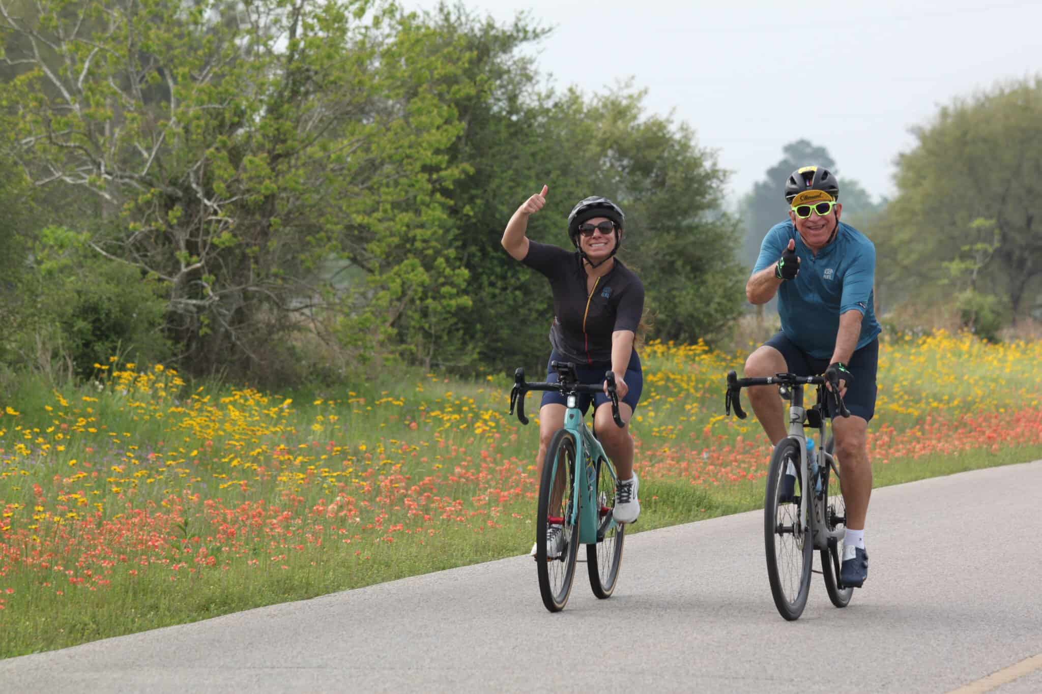 Enjoying a scenic bike ride on Bluebonnet Express trail with colorful wildflowers and lush greenery.