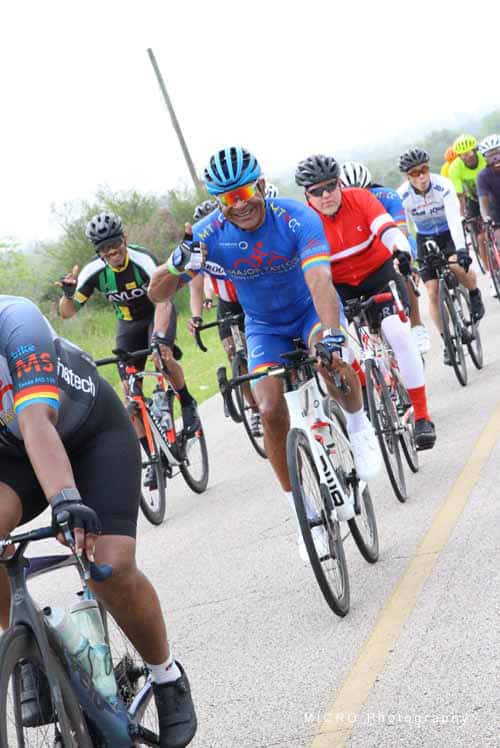 Brightly colored cyclists participating in the Bluebonnet Express bike ride on a scenic road.