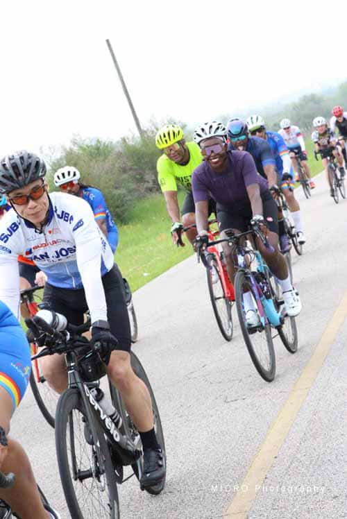 Vibrant group of cyclists participating in the Bluebonnet Express ride on a scenic rural road.