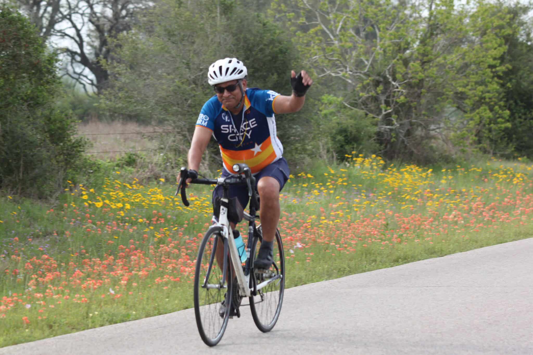 Vegan cyclist riding along scenic trail in Texas with Wildflowers, in a vibrant cycling jersey.