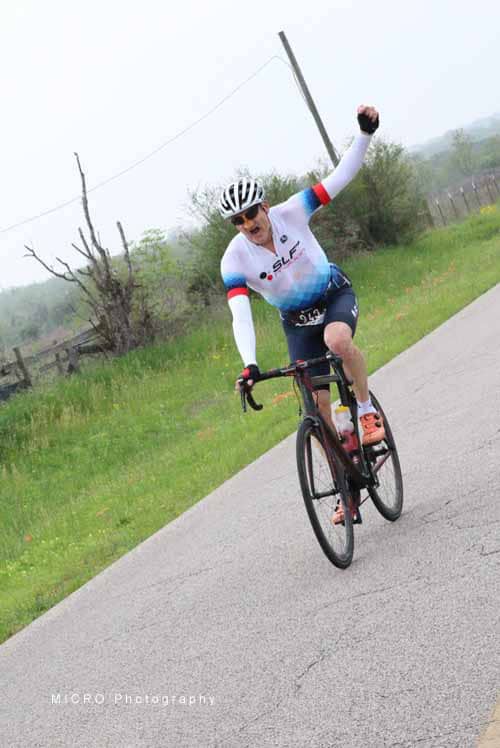 Bright cyclist celebrating victory on rural road during Bluebonnet Express race.
