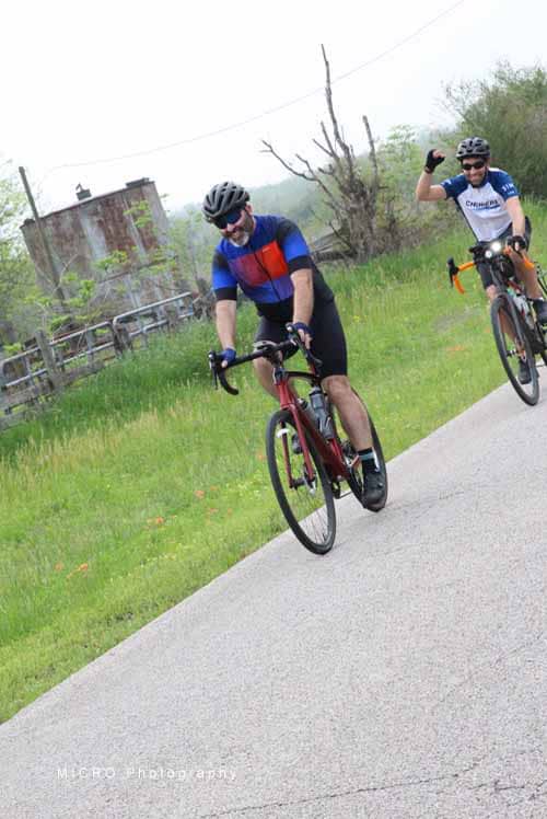 Brightly dressed cyclists enjoying a ride on a scenic rural trail during daytime, promoting outdoor activity and healthy lifestyle.
