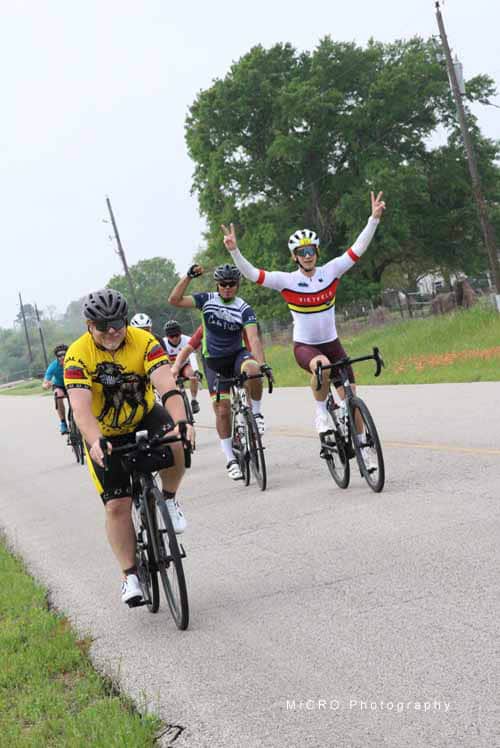 1. Group of cyclists enjoying a ride on a rural road during daytime, wearing colorful jerseys and helmets.
