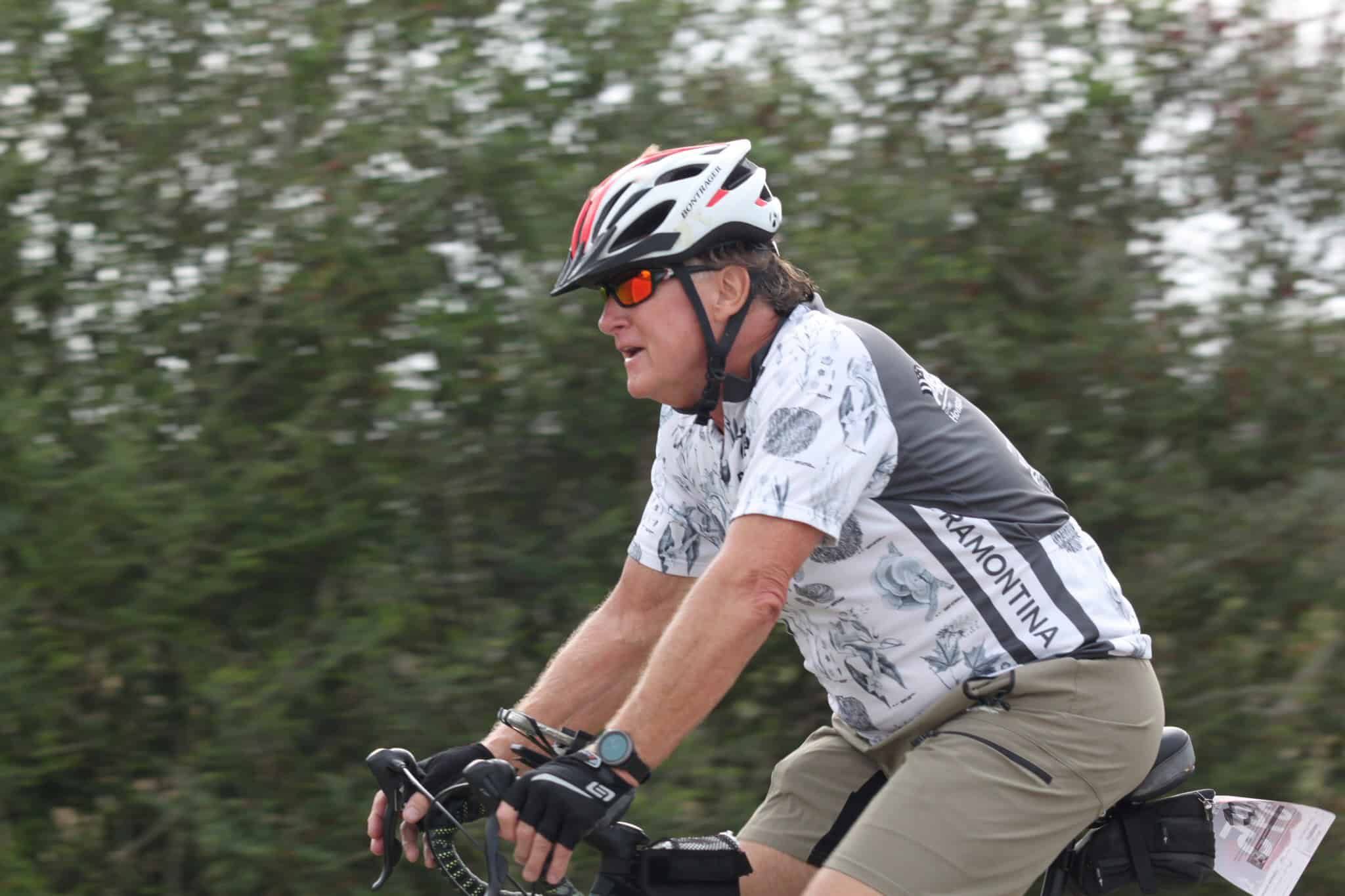 Vibrant cyclist wearing helmet and sunglasses enjoying a ride on a scenic trail.