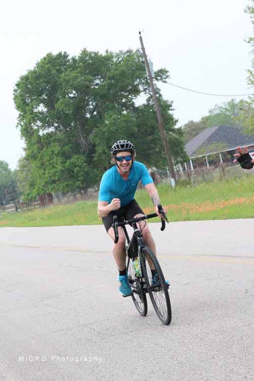 Vibrant cyclist riding downhill on a scenic open road during daytime.