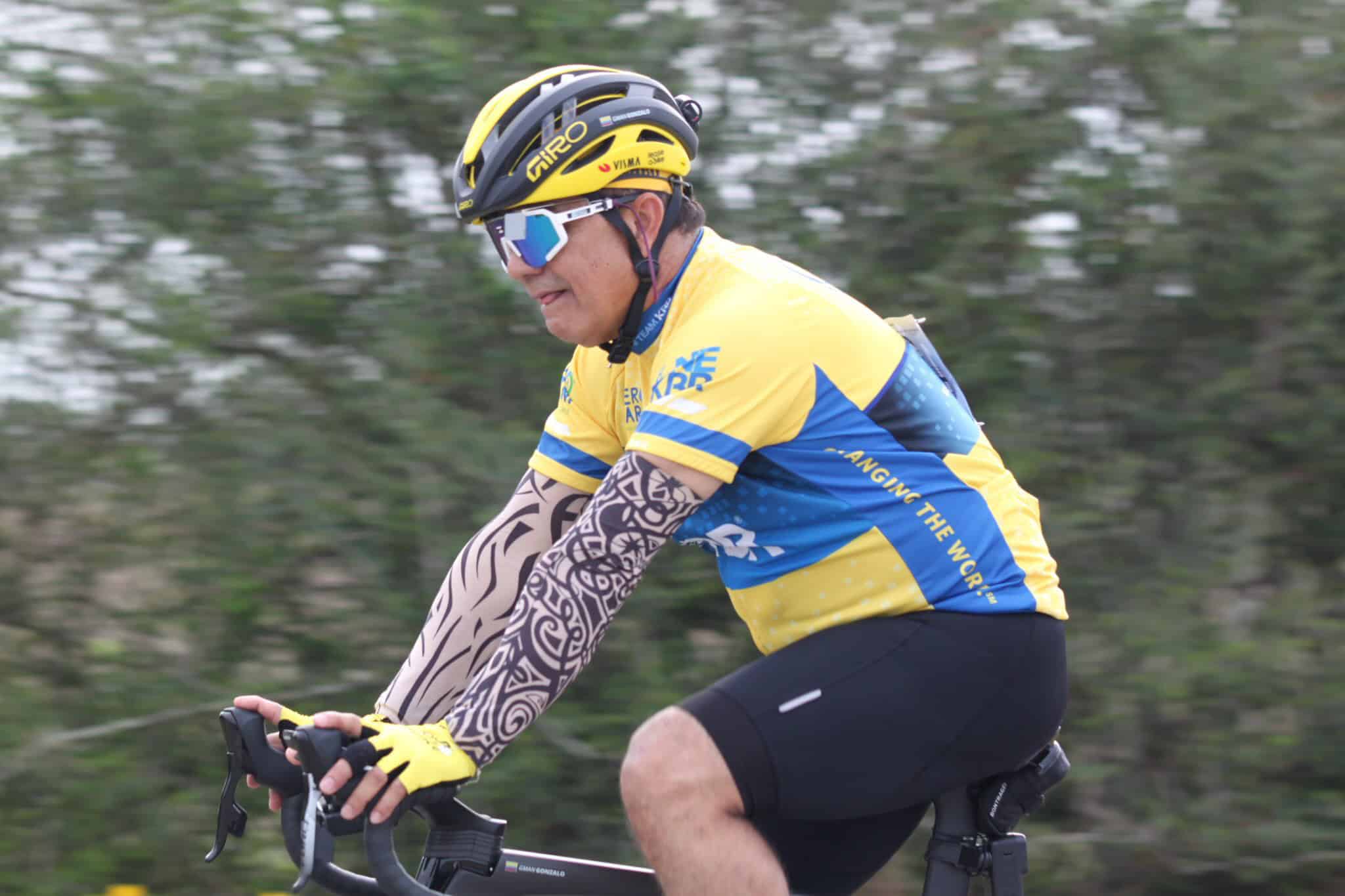 Vibrant yellow and blue cycling jersey with black shorts on a cyclist riding outdoors.